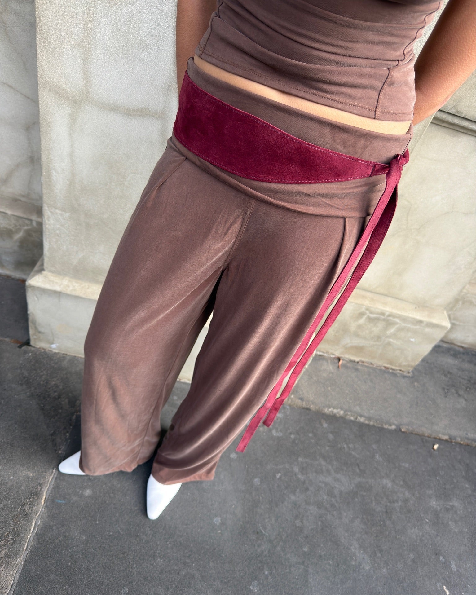 Detail of a burgundy suede wrap belt tied over wide-leg Serene Pant in Warm Brown.