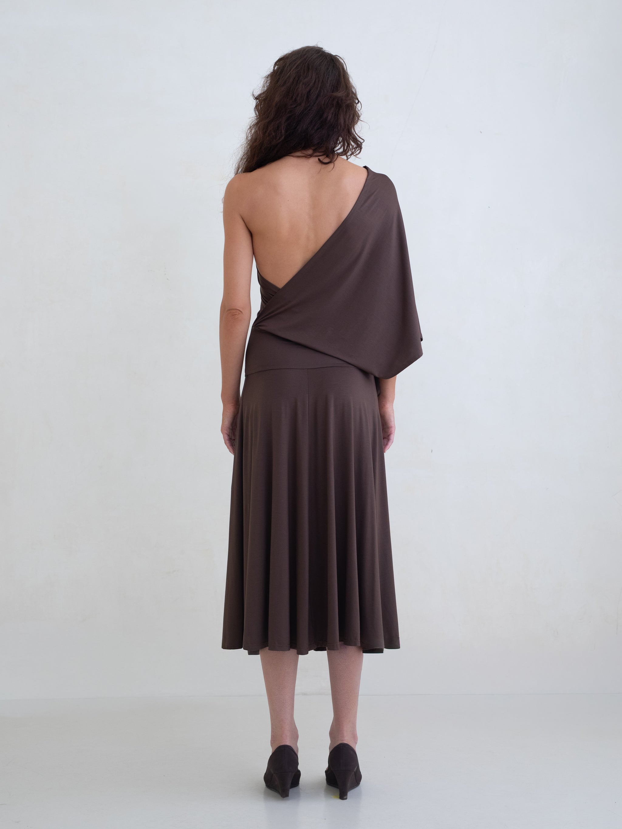 Woman wearing a brown one-shoulder midi dress on a white background