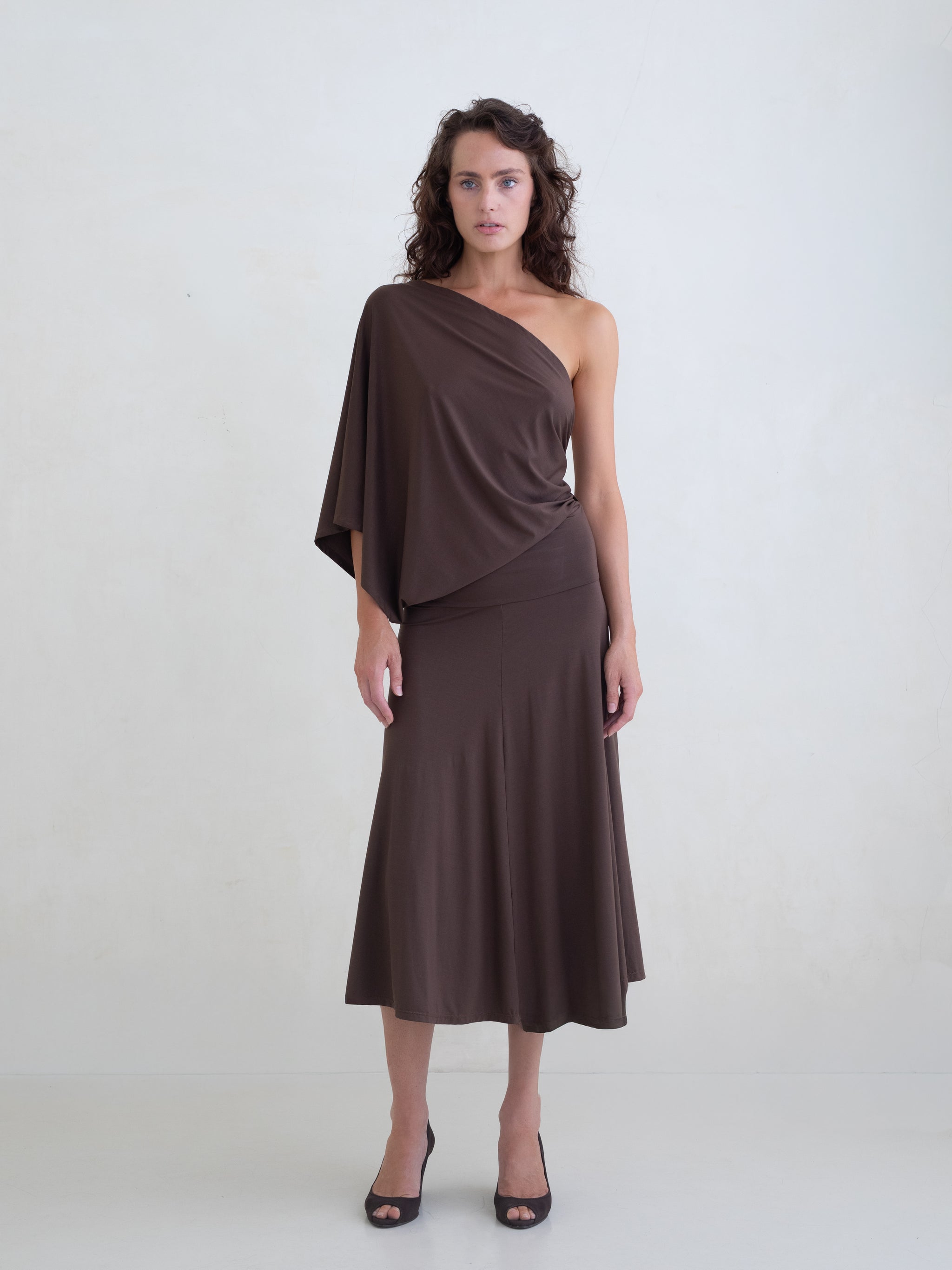 Woman wearing a brown one-shoulder midi dress on a white background.
