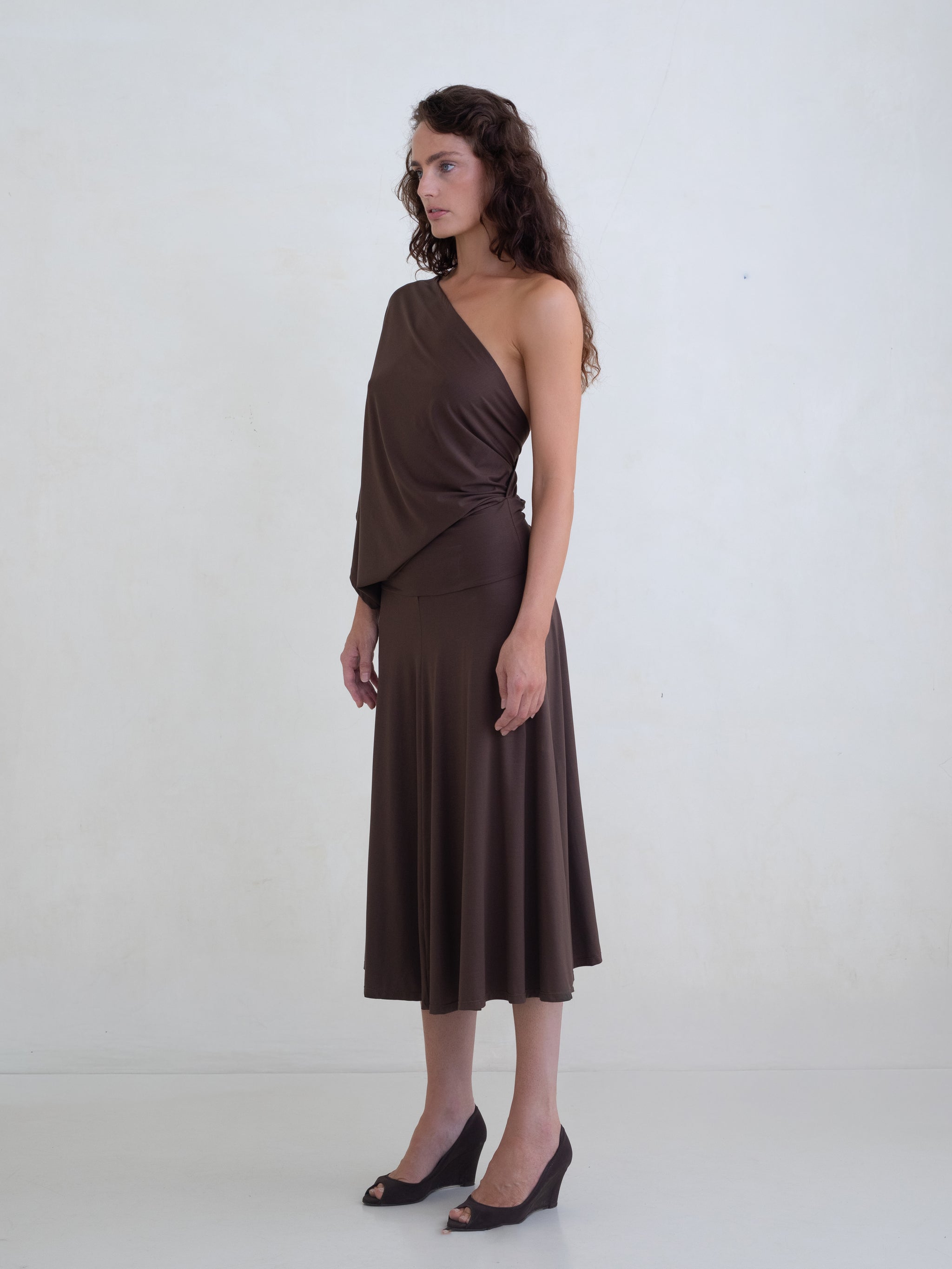 Woman wearing a brown one-shoulder midi dress on a white background 