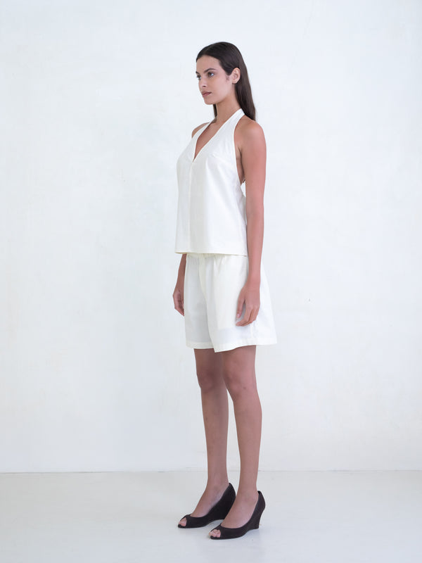 Woman wearing a cream v-neck halter top and matching cream boxer shorts on a white background. 