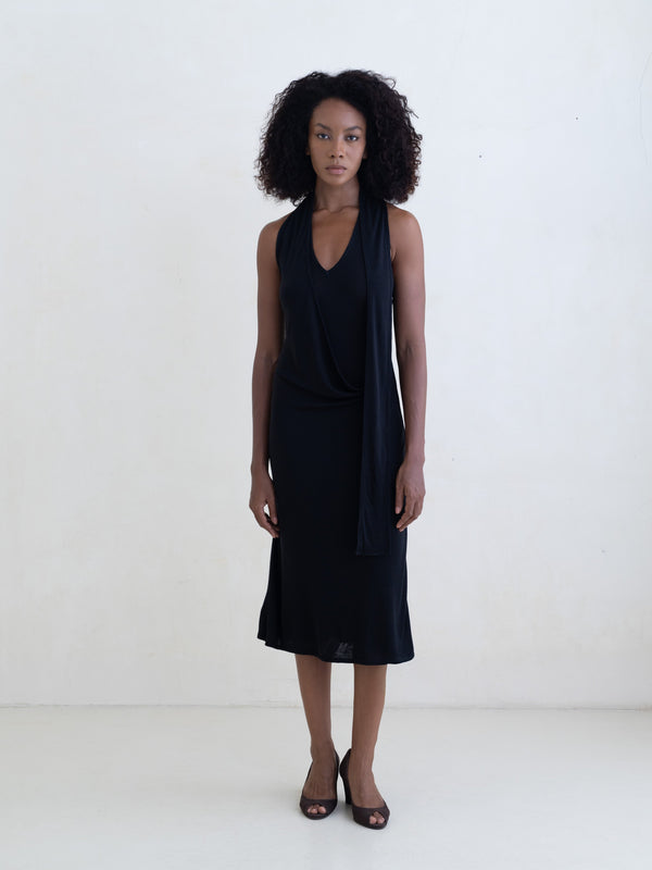 Woman wearing a black sleeveless V-neck midi dress on a white background.