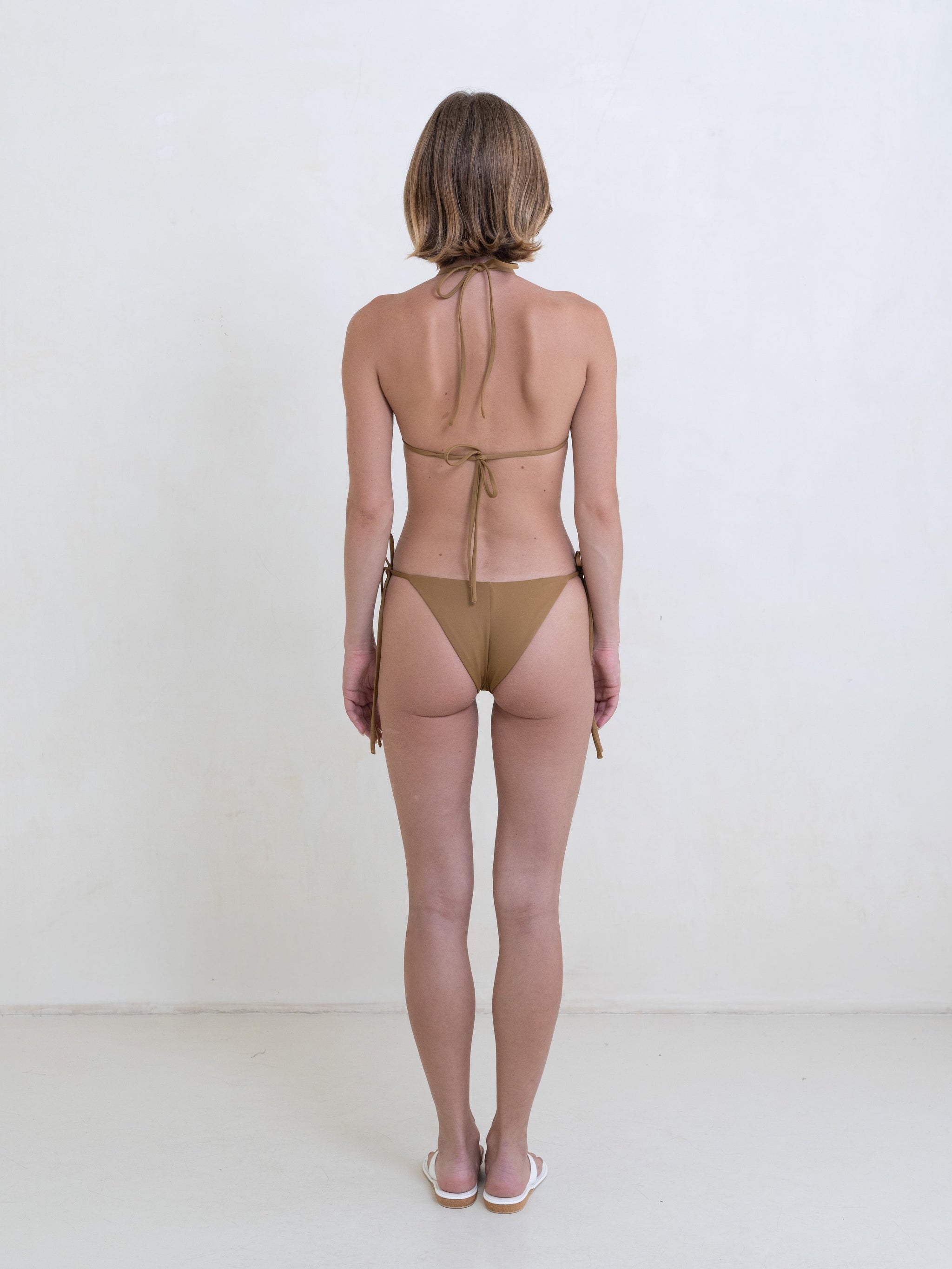 Woman wearing a golden brown bikini on a white background.