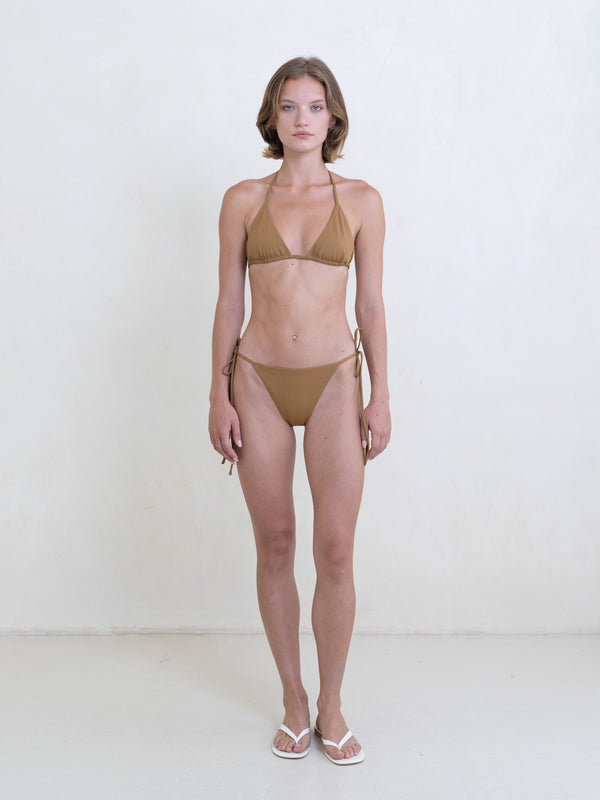 Woman wearing a golden brown bikini on a white background.