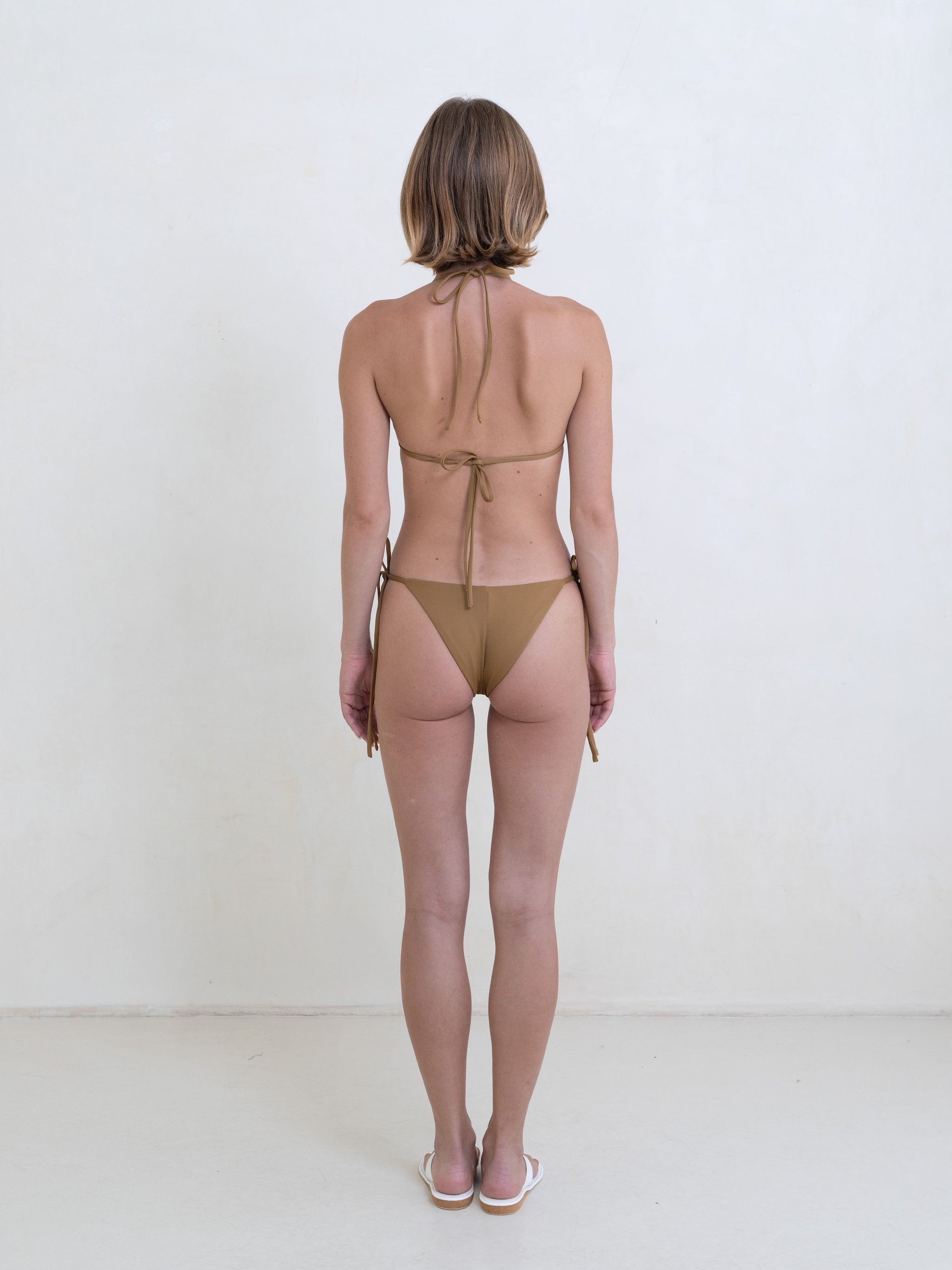 Woman wearing a golden brown bikini on a white background.