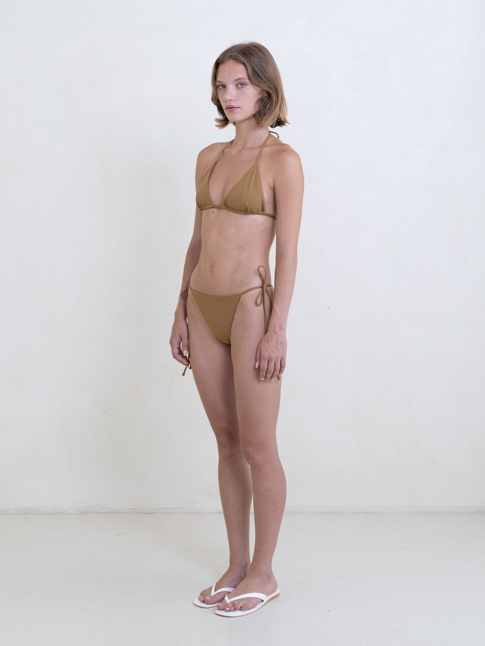 Woman wearing a golden brown bikini on a white background.