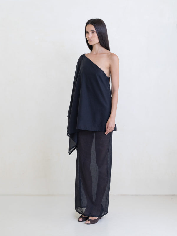 Woman wearing a black asymmetric maxi dress on a white background. 
