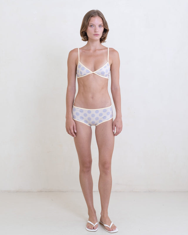 Woman wearing a gray polka dot bikini with a contrast white trim on a white background.