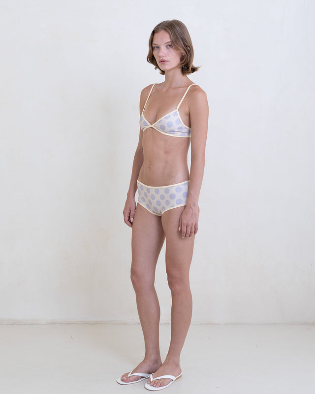 Woman wearing a gray polka dot bikini with a contrast white trim on a white background.