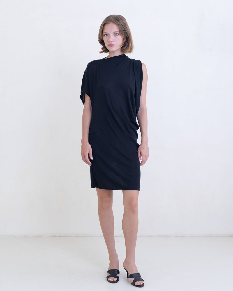 Woman wearing a black asymmetric mini dress on a white background. 
