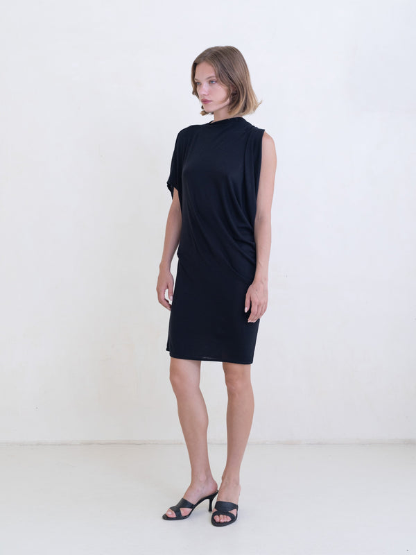 Woman wearing a black asymmetric mini dress on a white background. 