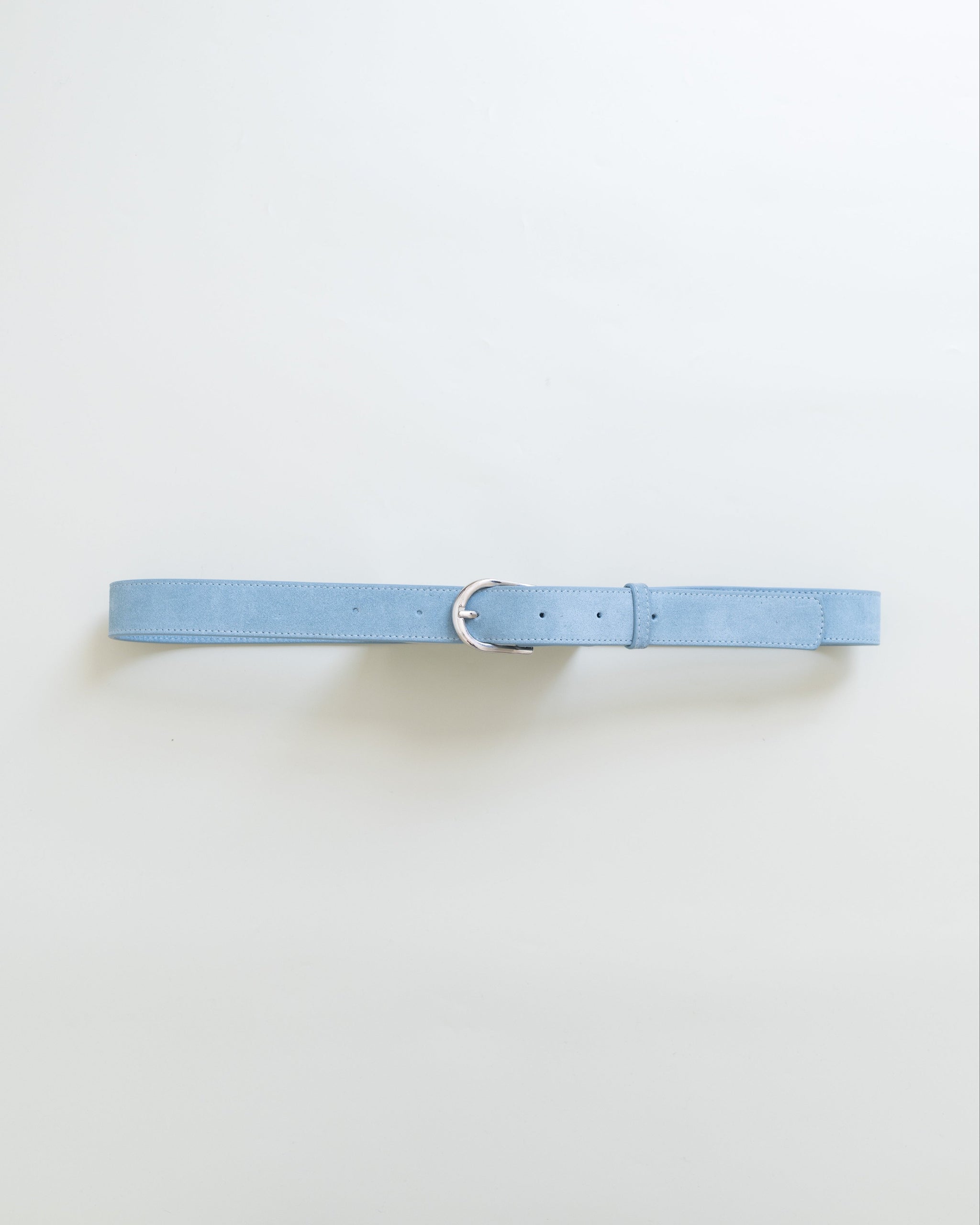 A light blue leather belt with silver metal buckle on a white background. 