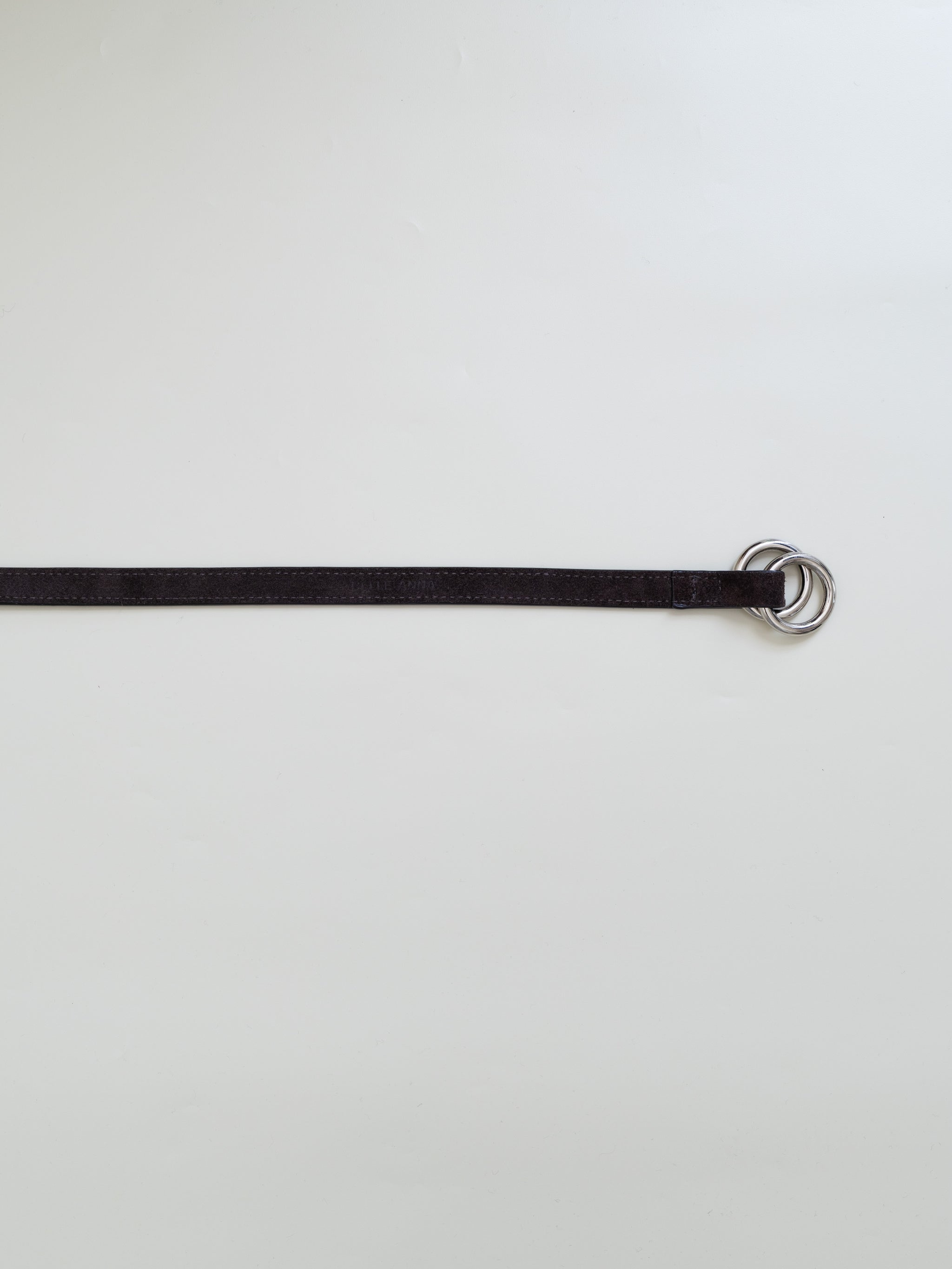 A brown leather belt with dual metal loops on a white background. 
