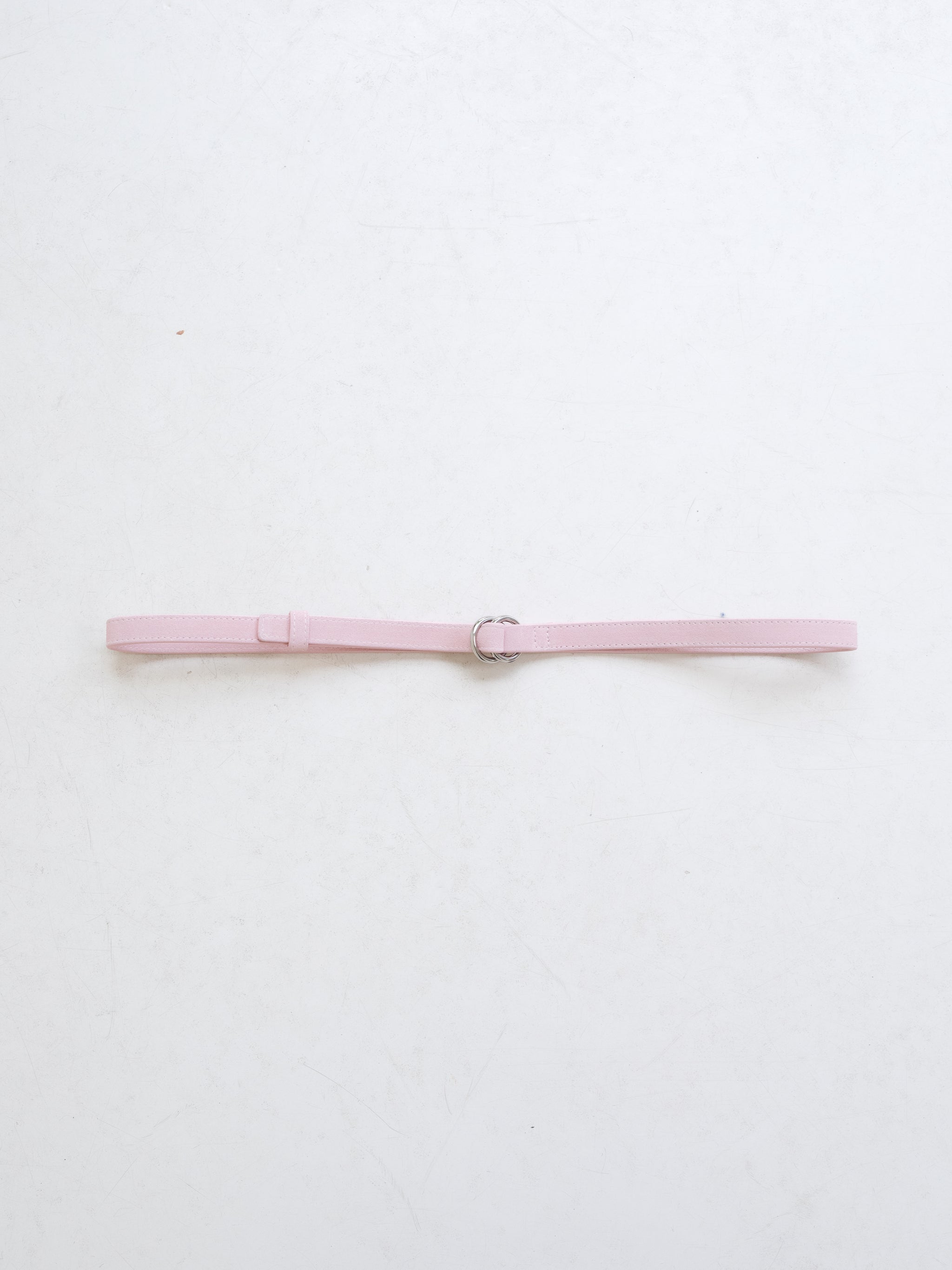 A light pink leather belt with dual metal loop closure on a white background. 