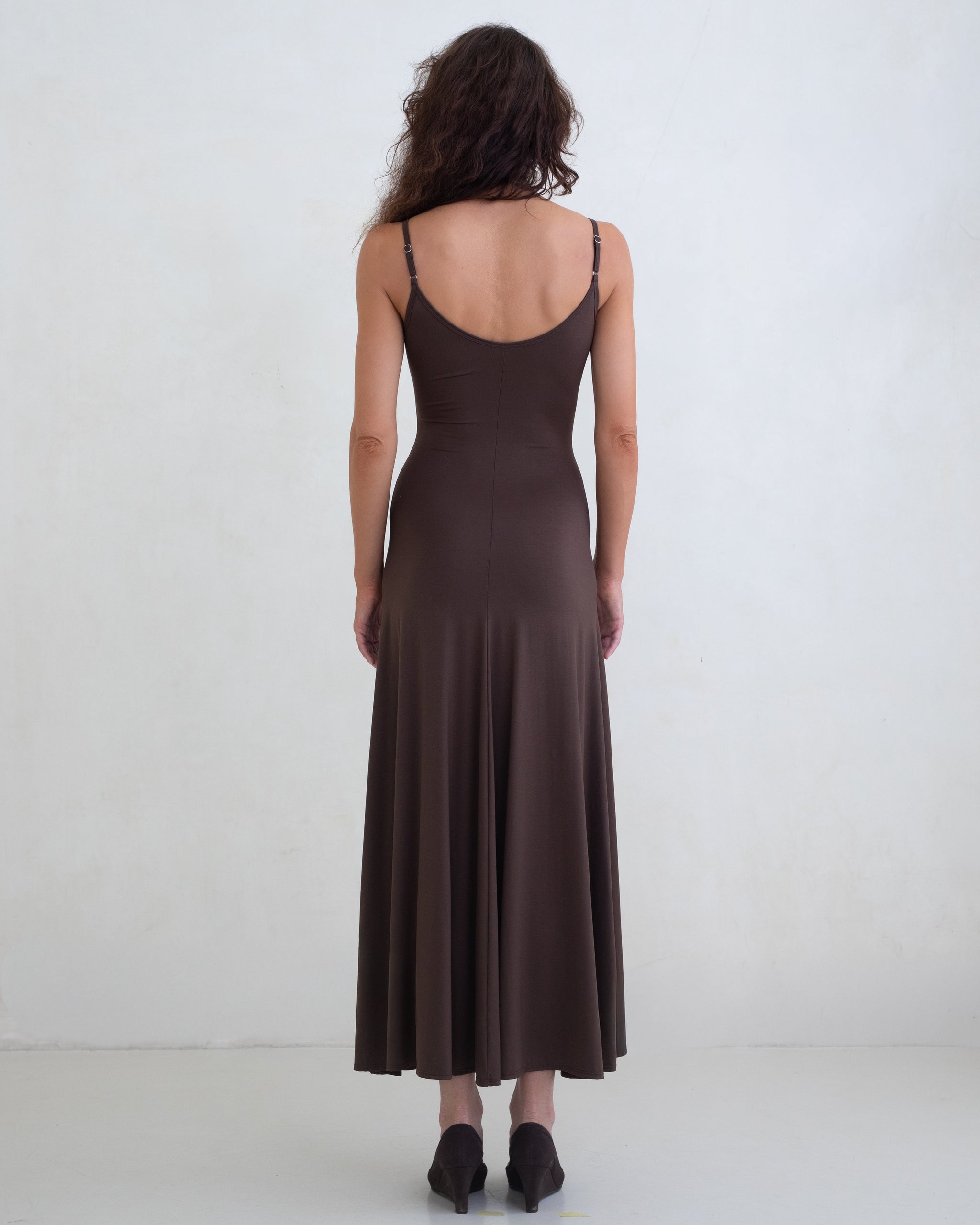Woman wearing a brown scoop neck slip dress on a white background. 
