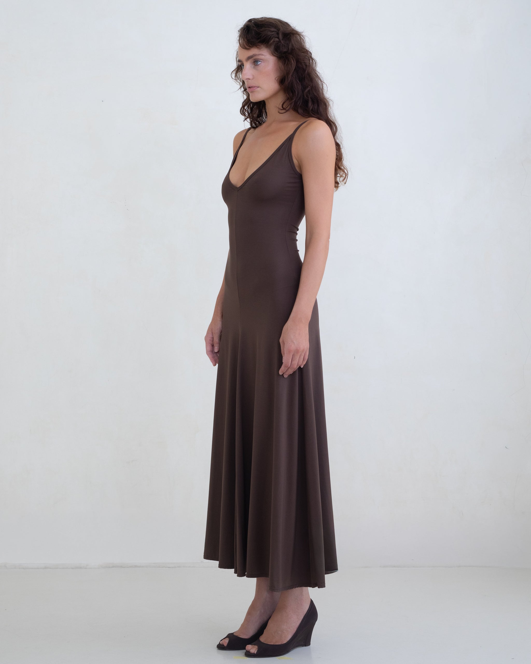 Woman wearing a brown scoop neck slip dress on a white background. 