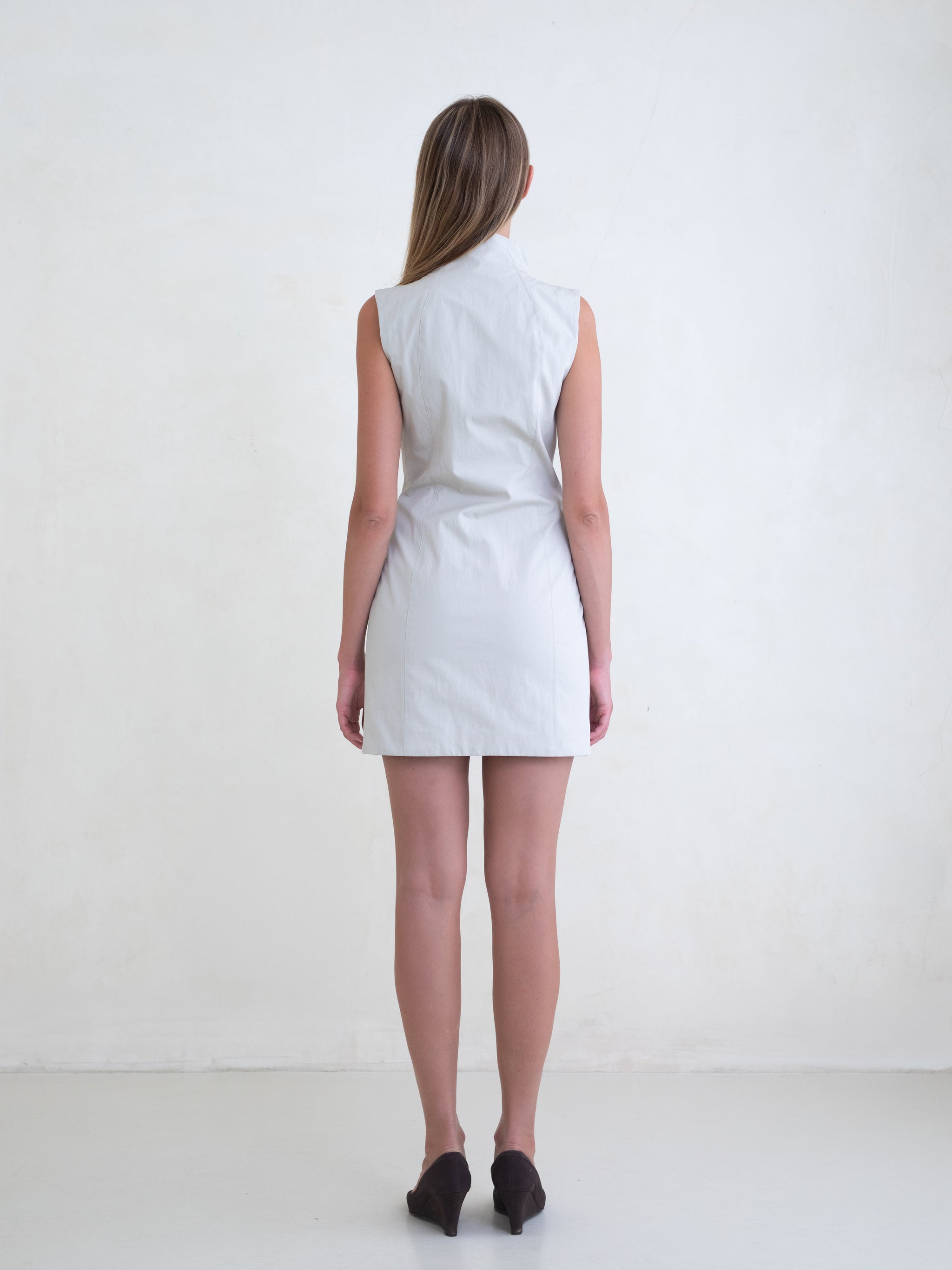 Woman wearing a light grey sleeveless mini dress on a white background 