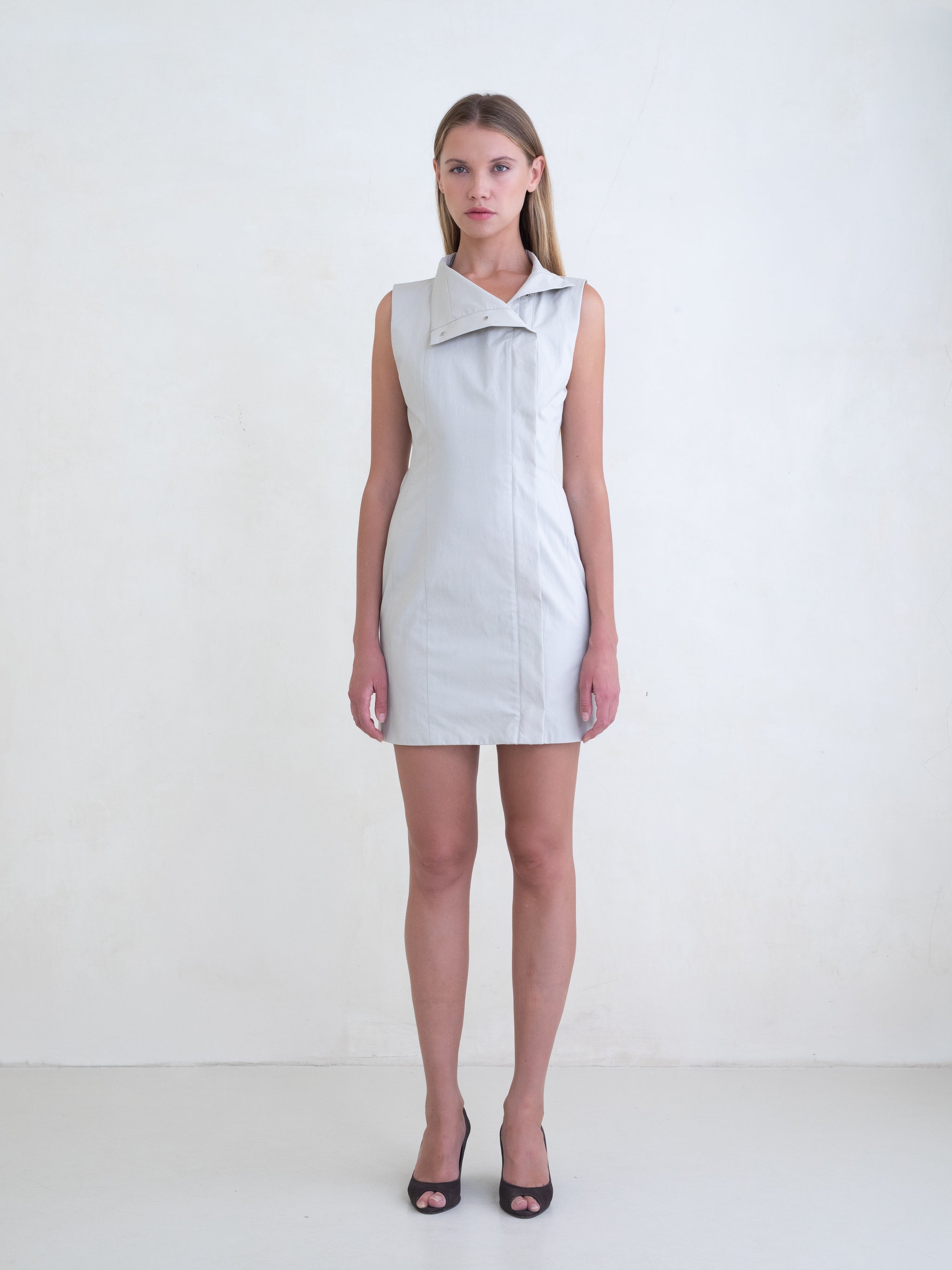 Woman wearing a light grey sleeveless mini dress on a white background 
