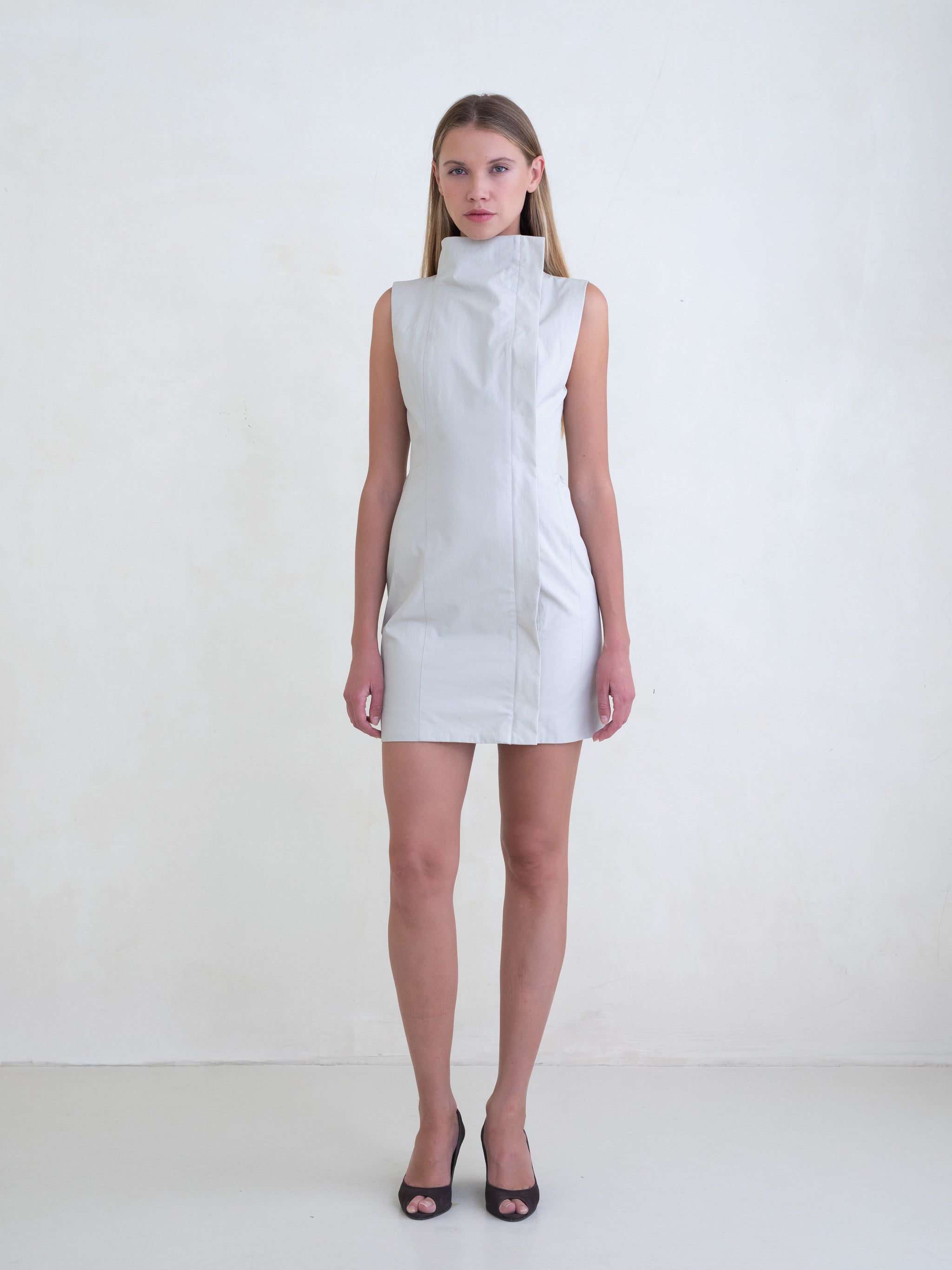 Woman wearing a light grey sleeveless mini dress on a white background 