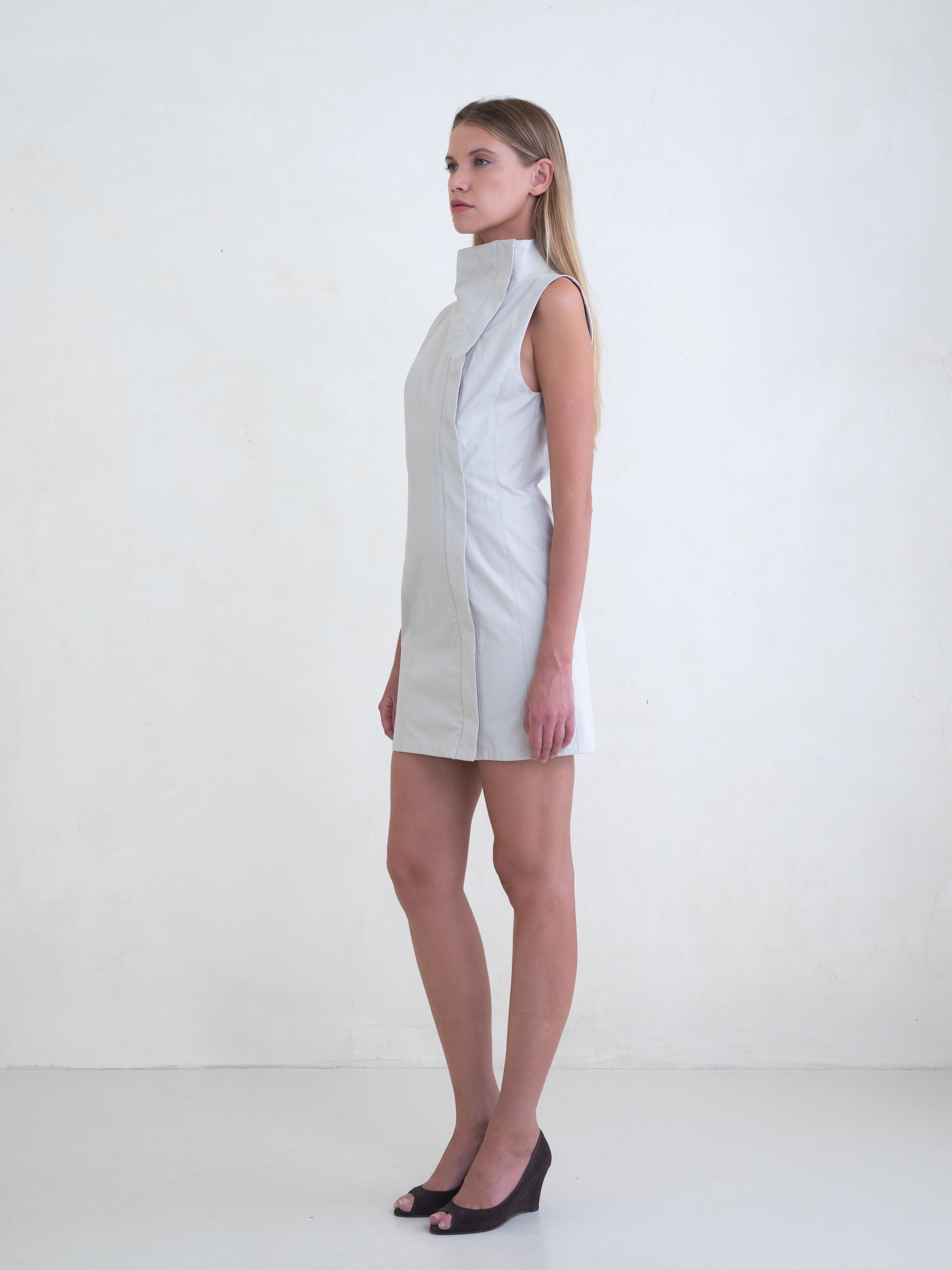 Woman wearing a light grey sleeveless mini dress on a white background 