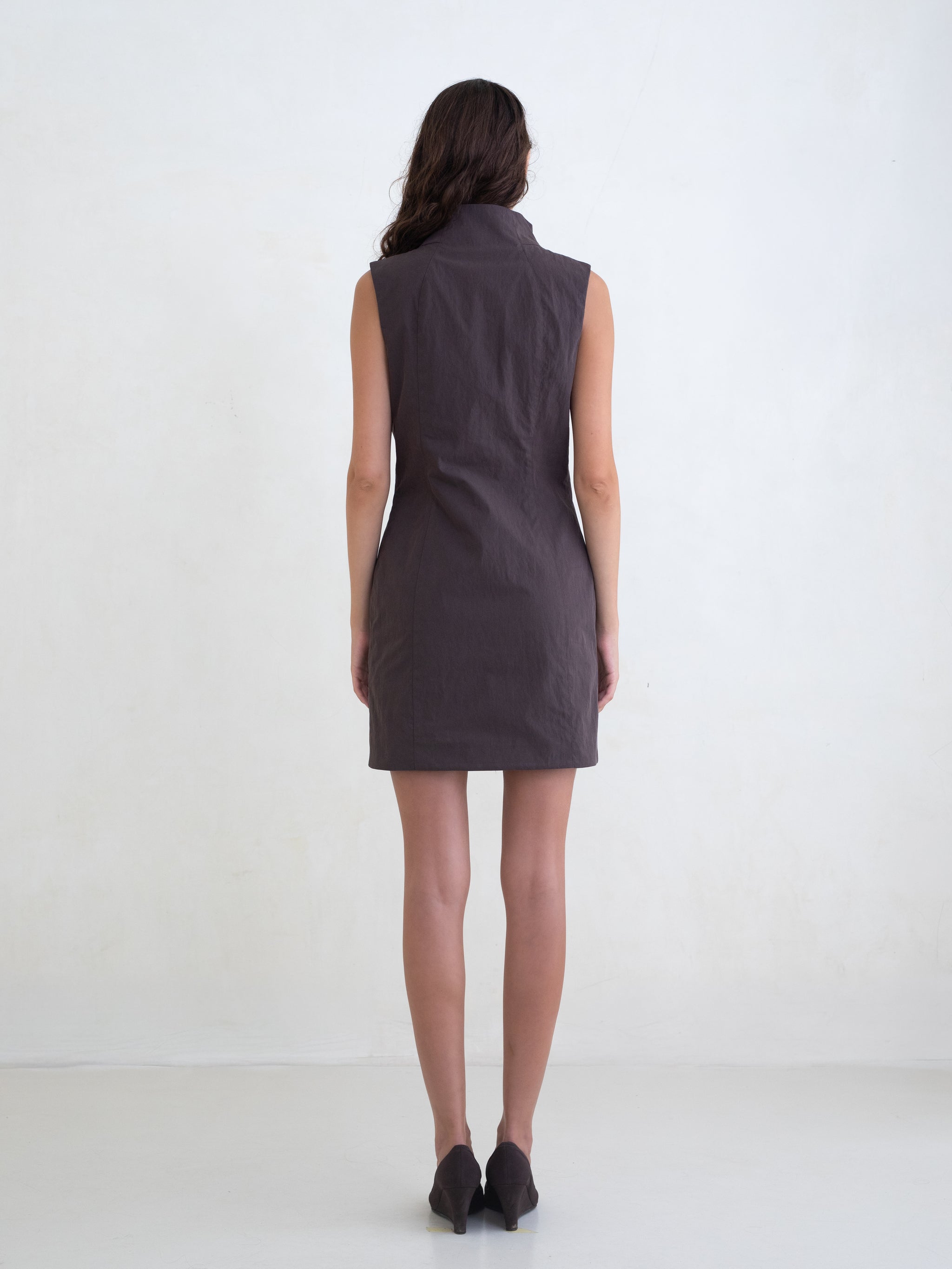 Woman wearing a brown sleeveless mini dress on a white background 