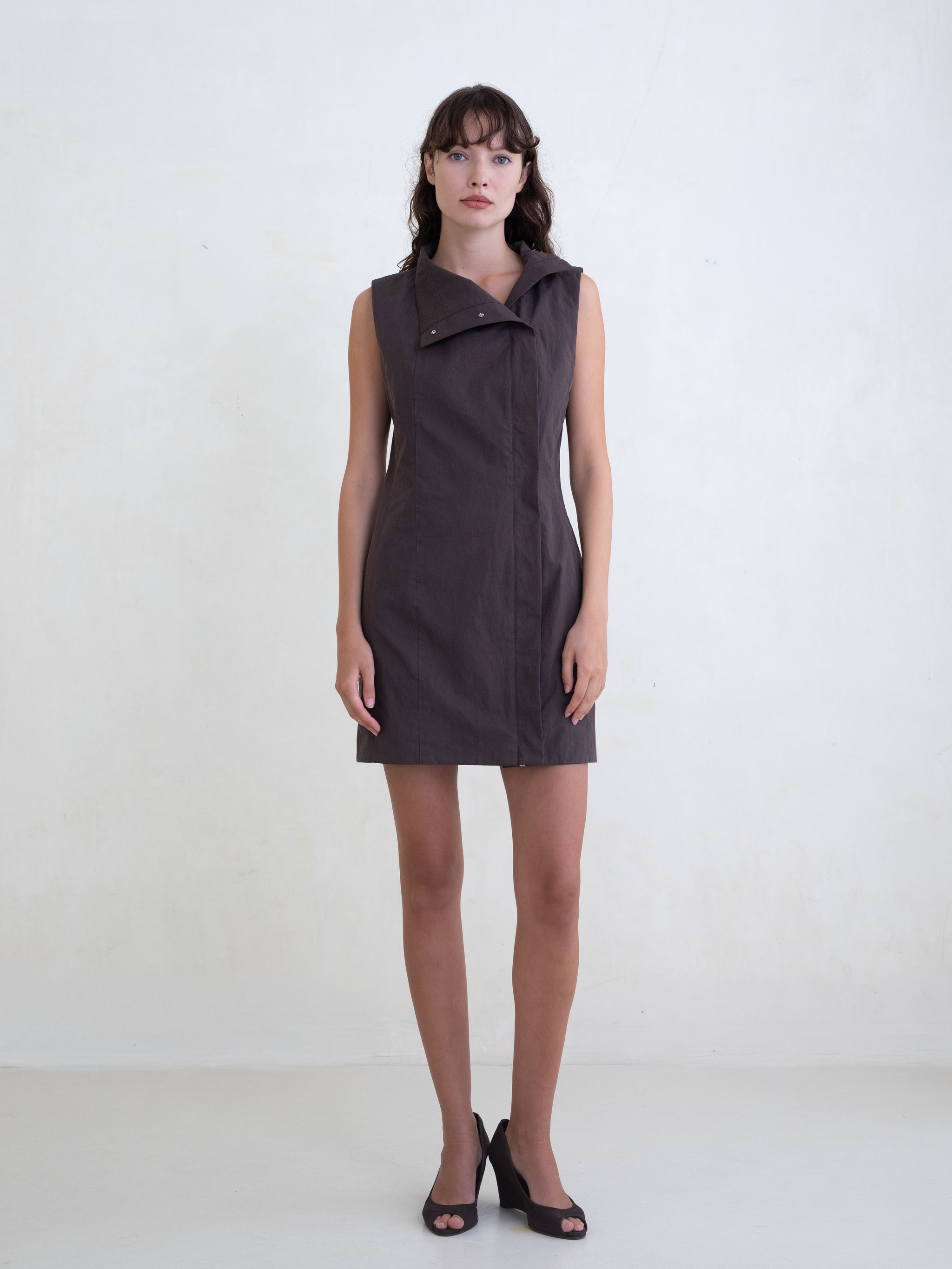 Woman wearing a brown sleeveless mini dress on a white background 