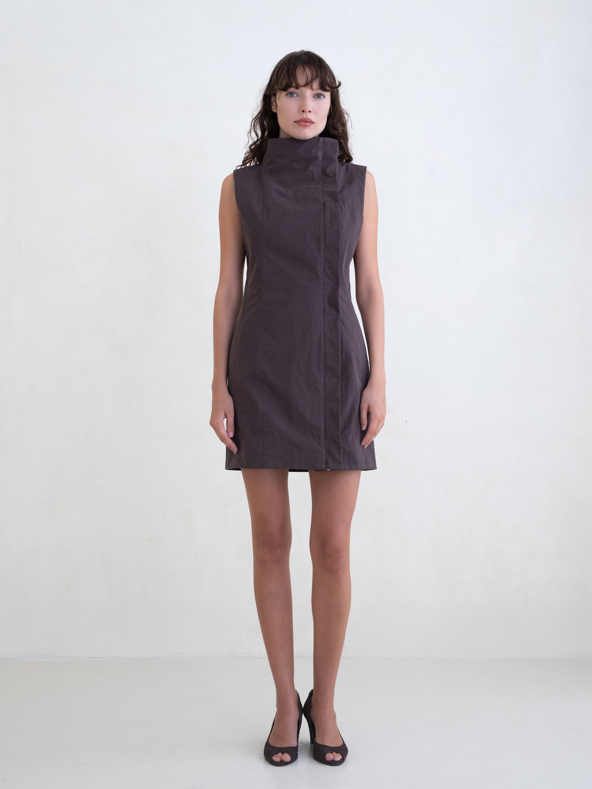 Woman wearing a brown sleeveless mini dress on a white background 