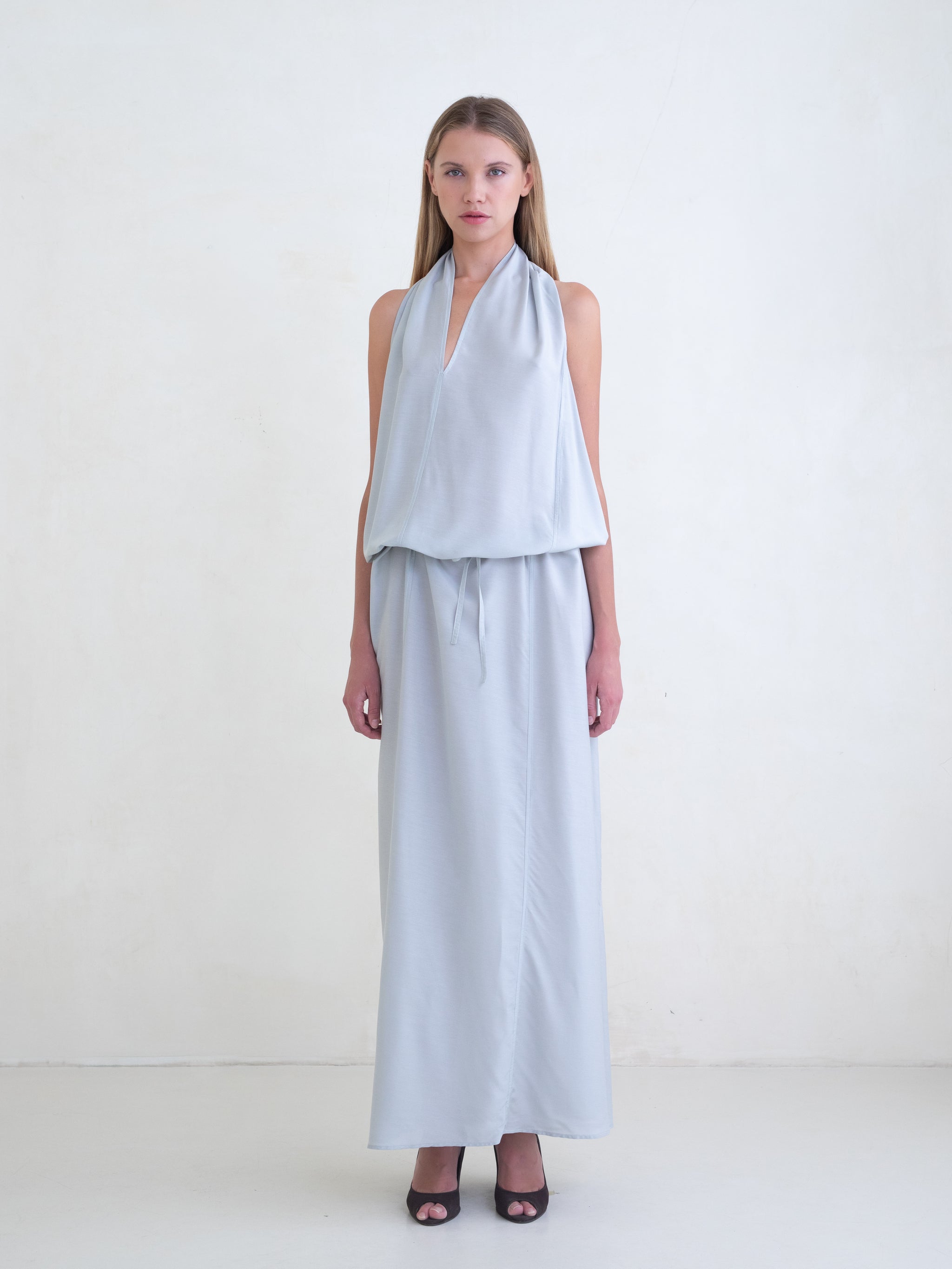 Woman wearing a light blue sleeveless maxi dress on a white background 