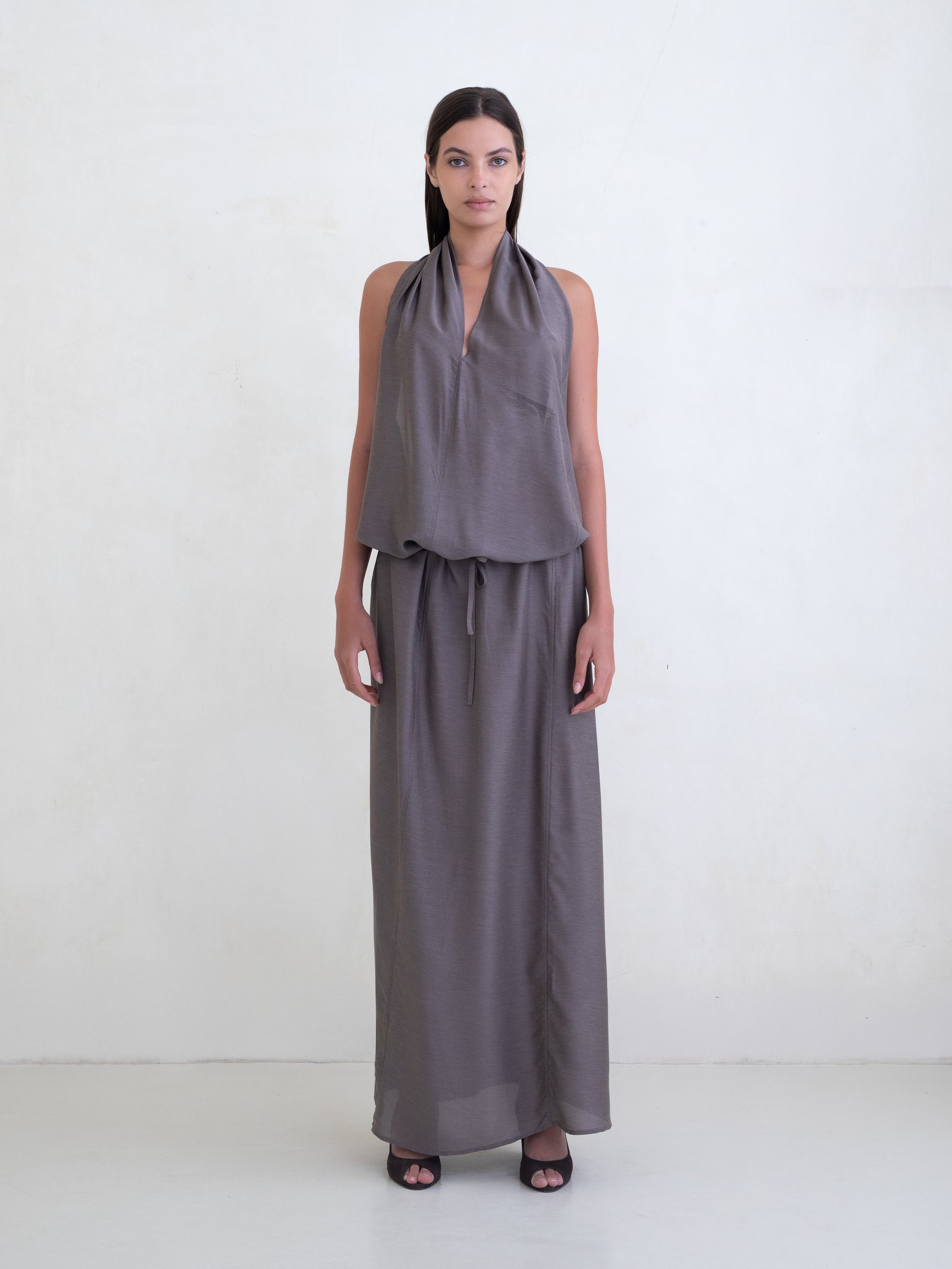 Woman wearing a taupe sleeveless maxi dress on a white background 
