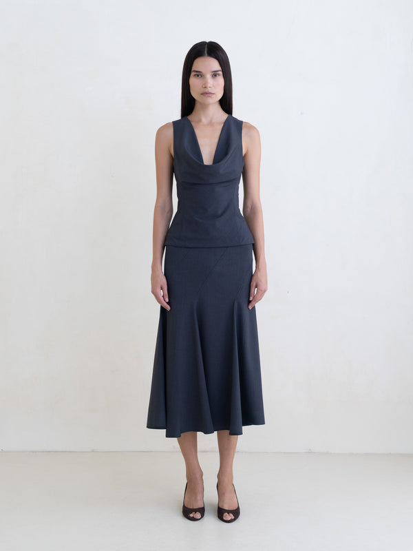 Woman wearing a dark gray sleeveless top and a dark gray flared midi skirt on a white background. 